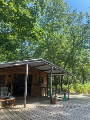 A wooden cabin with a covered porch, a table, and chairs outside.