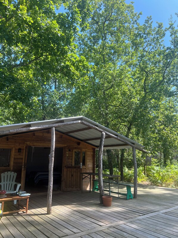 A wooden cabin with a covered porch, a table, and chairs outside.