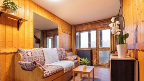 A cozy wooden interior with a sofa, a small table, and a potted plant. - Residence Arcelle, Ski In-Out with WiFi in Val Thorens, “V1” by Versant Collection (Val Thorens)
