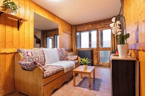 A cozy wooden interior with a sofa, a small table, and a potted plant. - Residence Arcelle, Ski In-Out with WiFi in Val Thorens, “V1” by Versant Collection (Val Thorens)