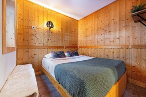 A wooden-paneled room with a bed, a bench, and a wall-mounted light fixture. - Residence Arcelle, Ski In-Out with WiFi in Val Thorens, “V1” by Versant Collection (Val Thorens)