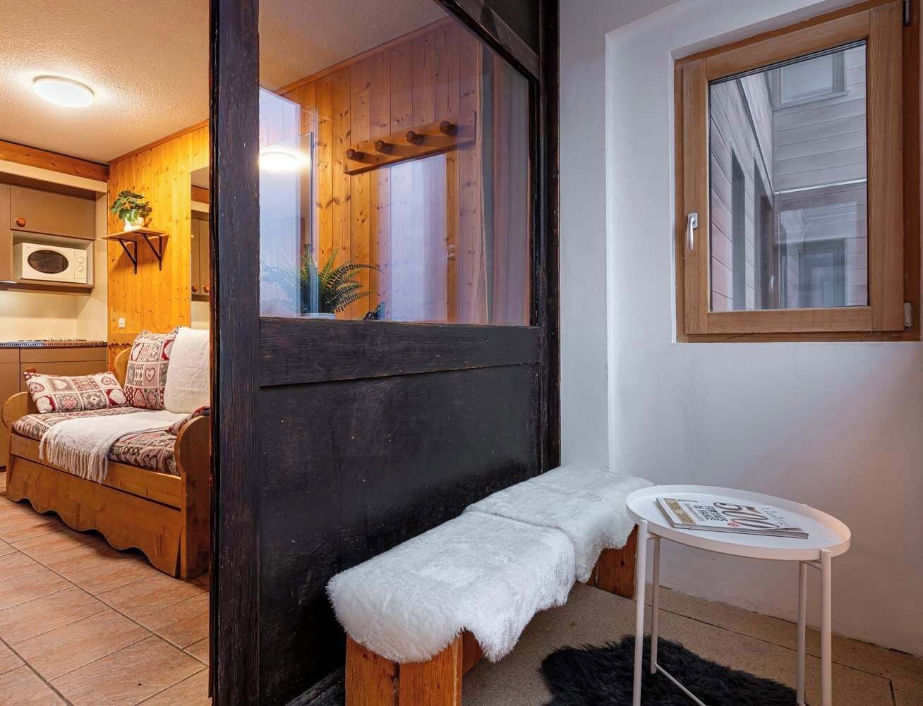 A cozy room with a wooden bench, a small table, and a bed with patterned bedding.