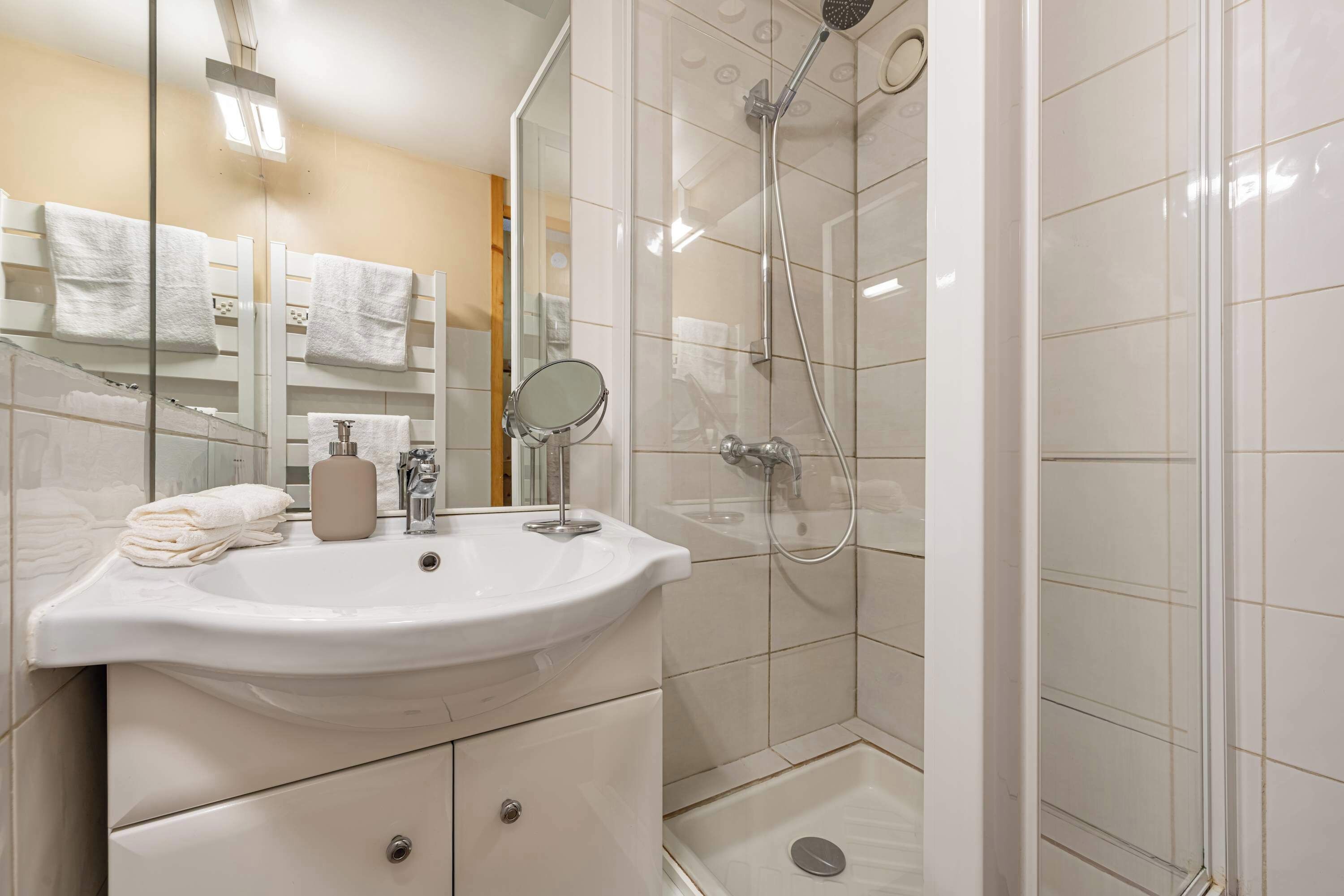 Ein modernes Badezimmer mit Waschbecken, Spiegel und Dusche.