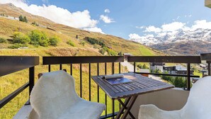 Ein Balkon mit Tisch und Stühlen mit Blick auf eine gebirgige Landschaft.