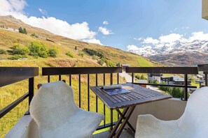A balcony with a table and chairs overlooking a mountainous landscape. - Residence Le Median, Ski In-Out with WiFi in Les Menuires, “V17” by Versant Collection (Les Belleville)