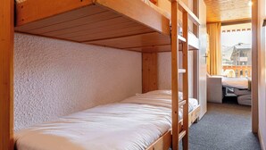 Habitación pequeña con literas, un escritorio y vistas a la montaña a través de una ventana.