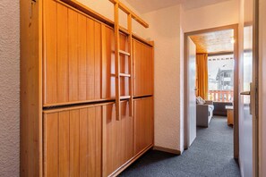 A hallway with wooden sliding doors, a ladder, and a view of a balcony with a sofa. - “V4” by Versant Collection (Val Thorens)