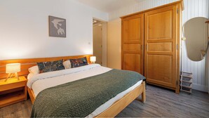 Una camera da letto con un letto, un armadio in legno, lampade sui comodini e un quadro appeso al muro.