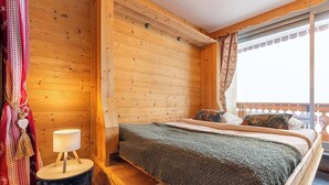 Habitación de cabaña de madera con cama, lámpara y ventana con cortinas.
