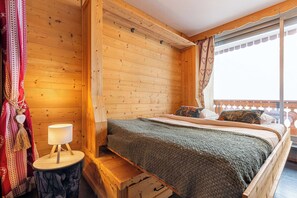 Ein Holzhütten-Zimmer mit einem Bett, einer Lampe und einem Fenster mit Vorhängen.