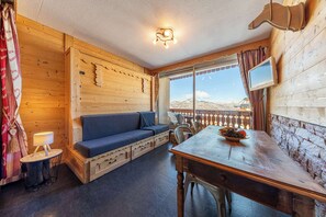 Ein gemütliches Holzhaus mit Sofa, Esstisch und Blick auf die Berge.