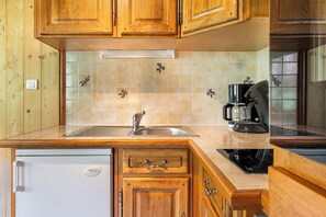 A kitchen with wooden cabinets, a stainless steel sink, a coffee maker, and a dishwasher. - Residence Olympic, Ski In-Out with WiFi in Val Thorens, “V11” by Versant Collection (Val Thorens)