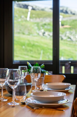 A dining table set with glassware and plates, overlooking a green landscape. - Residence Olympic, Ski In-Out with WiFi in Val Thorens, “V11” by Versant Collection (Val Thorens)