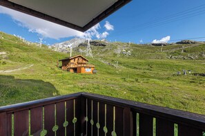 A wooden chalet with a balcony overlooking a mountainous landscape, ski lifts, and a clear sky. - “V11” by Versant Collection (Val Thorens)