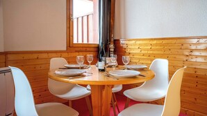 Ein Holzespeisetisch mit weißen Stühlen, ein Fenster mit Blick und ein Ski am Wand gelehnt.