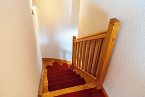 A wooden staircase with a red carpet, white walls, and a wooden handrail. - Residence Hermine, Ski In-Out with WiFi in Val Thorens, “V7” by Versant Collection (Val Thorens)