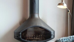 Ein modernes Wohnzimmer mit Kaminofen, einer Couch, einem Couchtisch und einer Stehlampe.