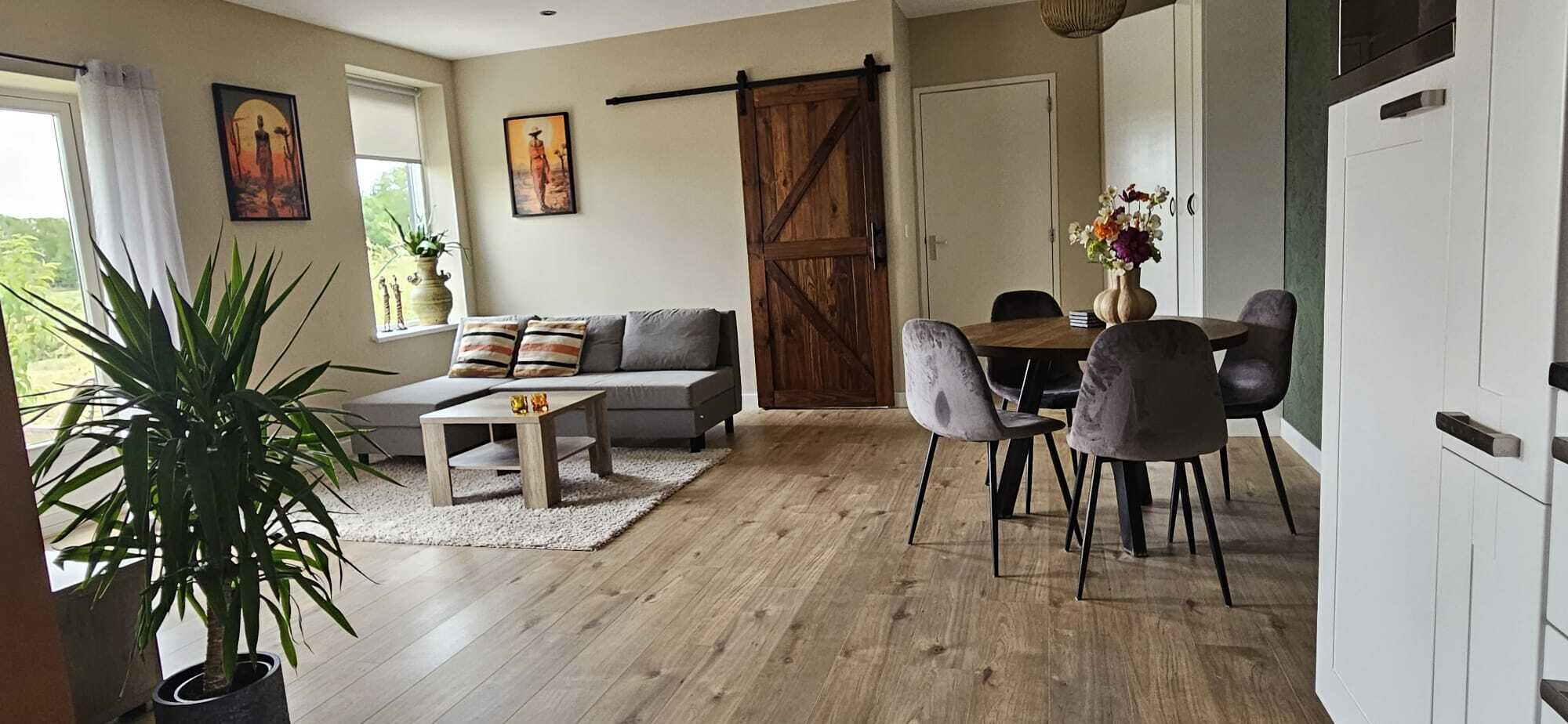 En moderne stue med sofa, sofabord og spiseplads med stole.