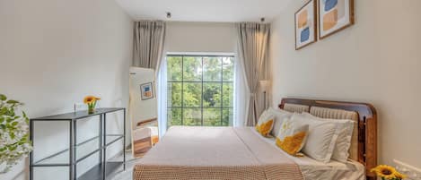 A bedroom with a bed, a bedside table, a nightstand, a ceiling fan, a window with curtains, and a wall-mounted shelf.