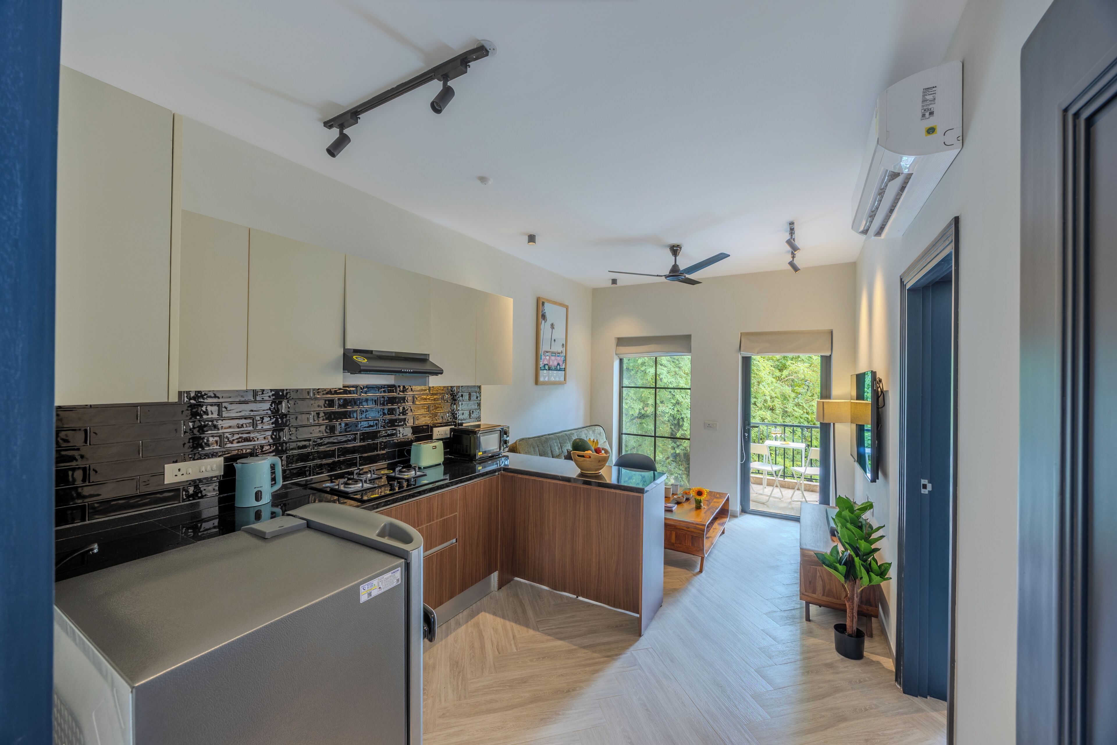 Una cocina moderna con estufa integrada, un comedor con mesa y sillas, y vistas al exterior.