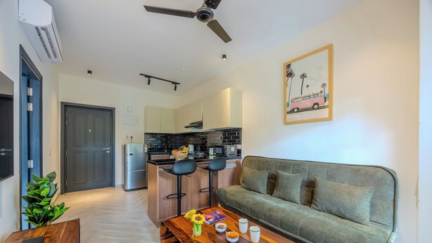 A modern living room with a sofa, a coffee table, and a kitchen in the background.