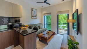 A modern kitchen with a dining area, a ceiling fan, and a large window with a view of greenery.