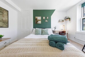 Ein Schlafzimmer mit Bett, Schreibtisch, Fenster und einer grünen Wand.