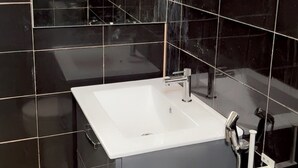 Ein Badezimmer mit einem weißen Waschbecken, einem Spiegel und einer Duschkabine.