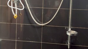 Ein Badezimmer mit Dusche, Toilette und einem fest installierten Steckdosenanschluss.