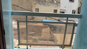 Ein Balkon mit Metallgeländer, Fliesenboden und Blick auf umliegende Gebäude.
