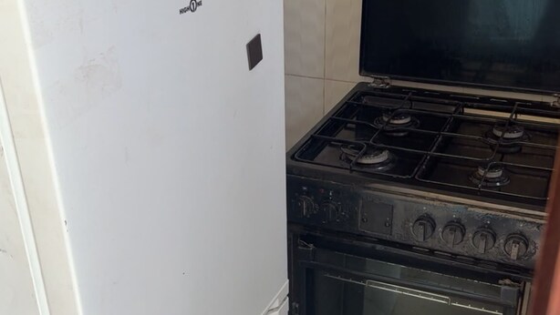 A kitchen with a white refrigerator, a black stove, and an oven.