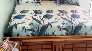 A bed with a floral bedspread, wooden headboard, and a nightstand with a newspaper.
