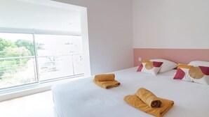 Hotellihuone, jossa on suuri sänky, valkoiset vuodevaatteet ja näkymä ikkunasta.