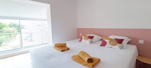 A hotel room with a large bed, white bedding, and a view through a window. - Luxury Villa for 14 People: 7 Bedrooms, 7 Bathrooms, 3 Kitchens, Pool, and Spa (Les Sables-d'Olonne)