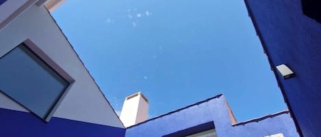 A modern building with a blue exterior, large windows, and a clear sky view.