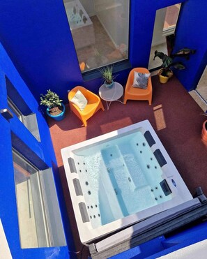 A hot tub in a blue room with two orange chairs and a small table. - Luxury Villa for 14 People: 7 Bedrooms, 7 Bathrooms, 3 Kitchens, Pool, and Spa (Les Sables-d'Olonne)