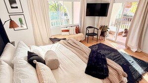 Un dormitorio con una cama grande, un televisor montado en la pared y vistas al exterior a través de la ventana.