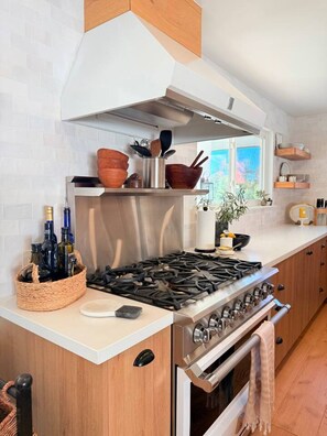 A modern kitchen with a gas stove, wooden cabinets, and a stainless steel range hood. - Lavender House + Guest Suite - Sleeps 11 (Ojai)