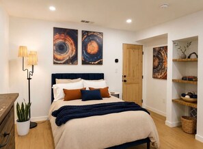 A bedroom with a bed, bedside lamps, a potted plant, and artwork on the walls. - Lavender House + Guest Suite - Sleeps 11 (Ojai)