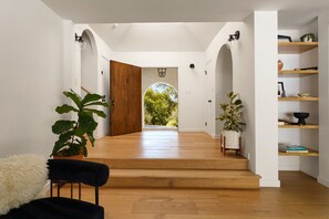 A spacious hallway with wooden flooring, a large wooden door, and a view of greenery outside. - Lavender House + Guest Suite - Sleeps 11 (Ojai)