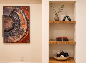 A wall with a large abstract painting and a wooden shelf with decorative items. - Lavender House + Guest Suite - Sleeps 11 (Ojai)