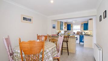 A dining area with a table and chairs, a kitchen with blue cabinets, and a view of the living area.
