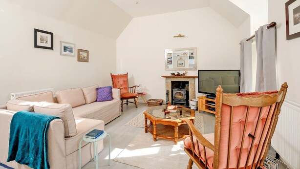 A living room with a sofa, armchair, coffee table, fireplace, television, and framed pictures on the wall. - Cosy Aberdeenshire Stone Cottage (Inverurie)