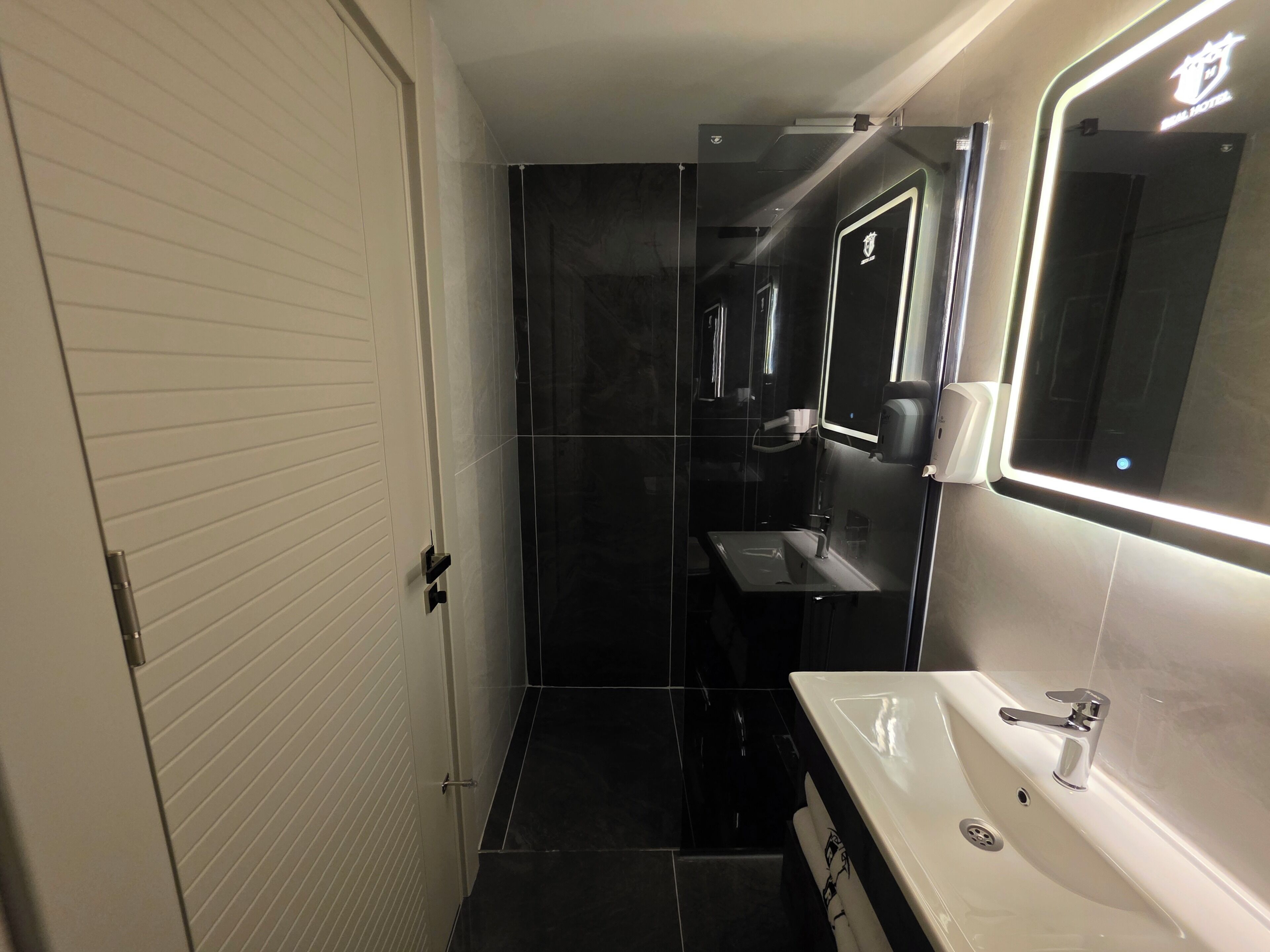 Un bagno moderno con un lavandino bianco, uno specchio e un water.