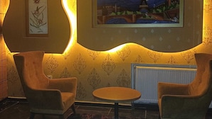 Una habitación con dos sillones, una mesita redonda, un cuadro enmarco y un radiador.