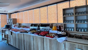 Montaje de bufé con diversas opciones de comida, una estación de bebidas y cristalería.