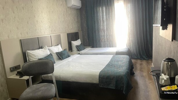 Una habitación de hotel con dos camas, un escritorio, una silla, cafetera y televisión.