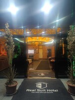 La entrada del Hotel Real Suit, con un mostrador de recepción, una araña de cristal y un cartel de recepción.