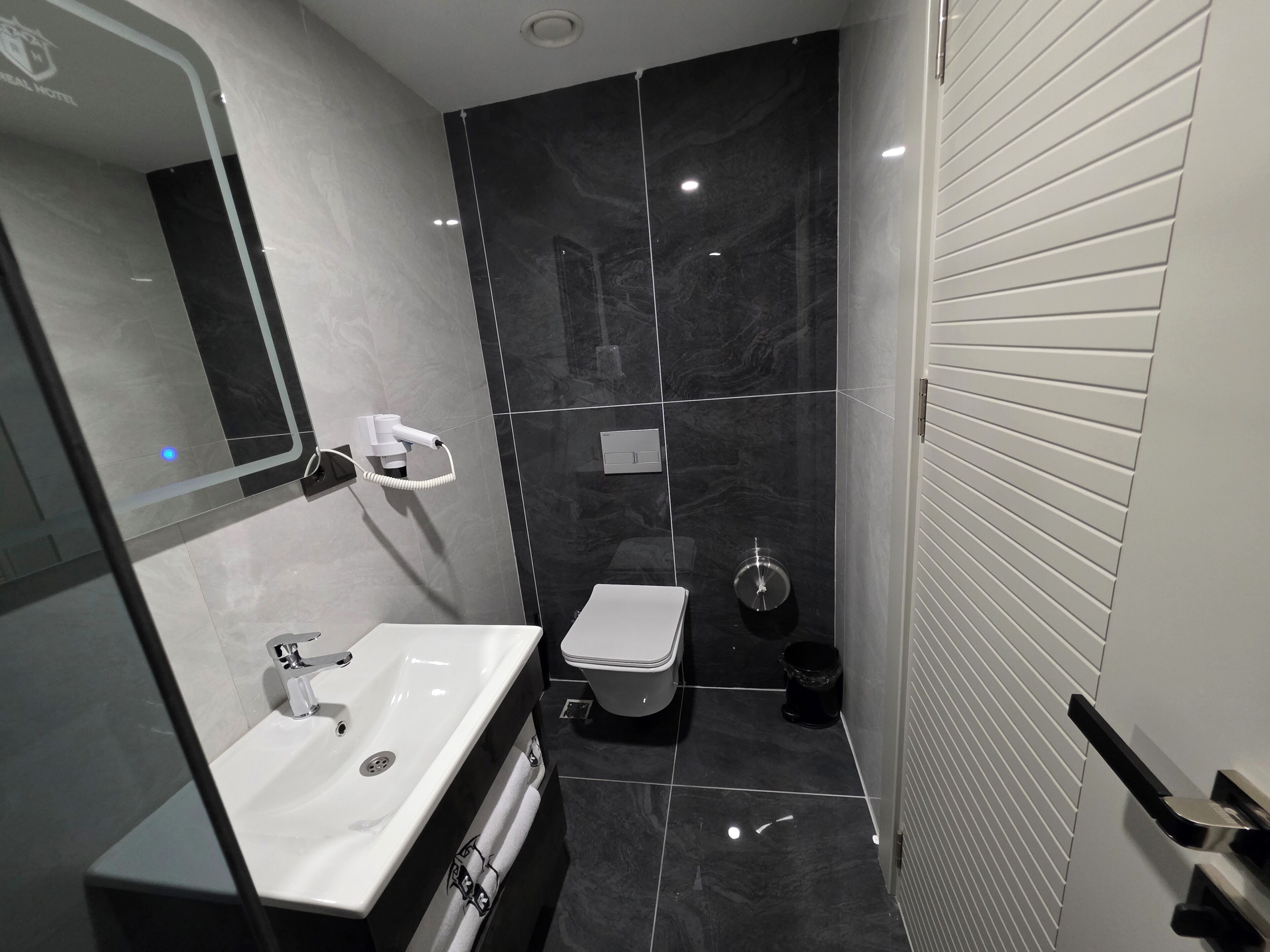 A modern bathroom with a white sink, a toilet, and a shower area.