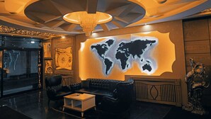Un hall con un mural de un mapa mundial, una araña y un sofá de cuero.
